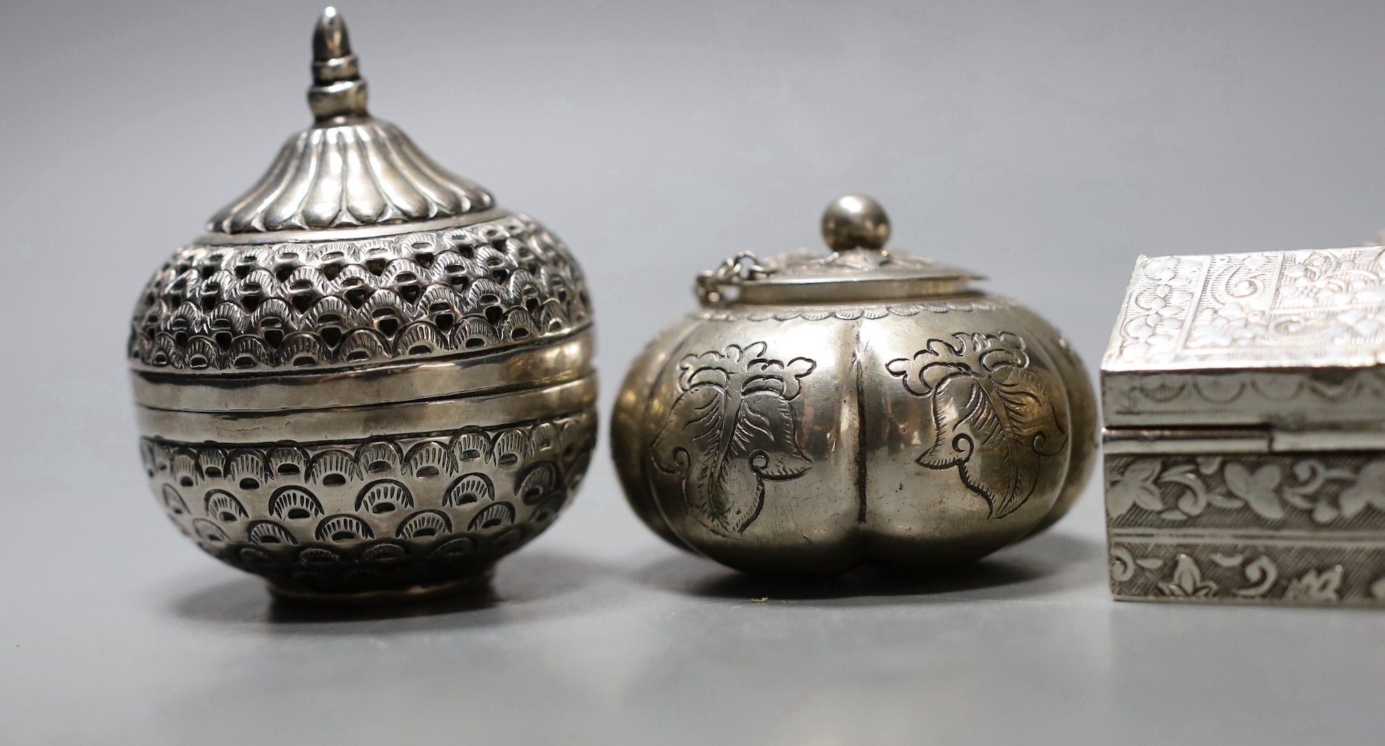 Five assorted 20th century Indian white metal circular boxes and covers including betel nut boxes and one other house shaped box and cover, largest diameter approx. 71mm.